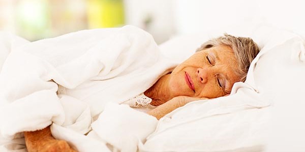 Elderly woman sleeping on a bed.