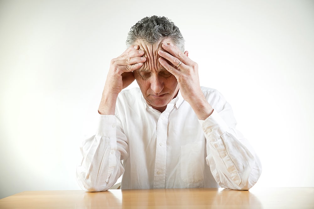 Elderly man with stress and a headache.