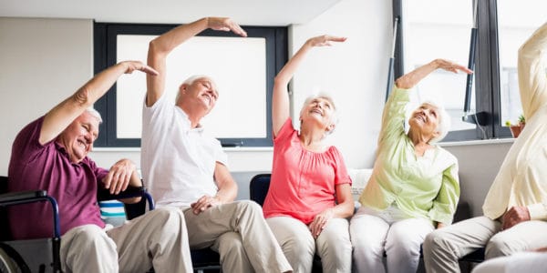 A group of elderly people enjoying an exercise class while being able to be seated.
