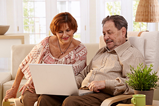 Elderly couple using laptop computer at home.