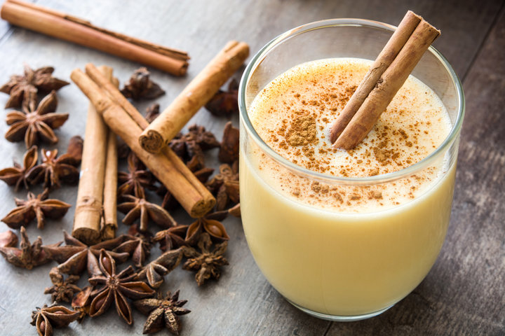 Homemade eggnog with cinnamon on wooden background. Typical Christmas dessert.