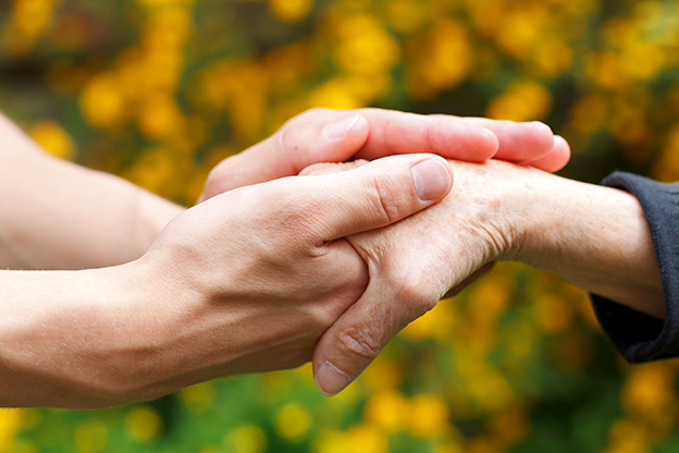 Doctor's hand holding a wrinkled elderly hand