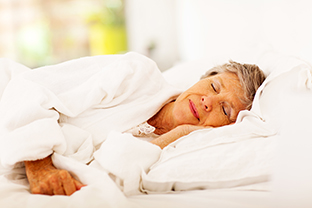 Elderly woman sleeping on a bed.