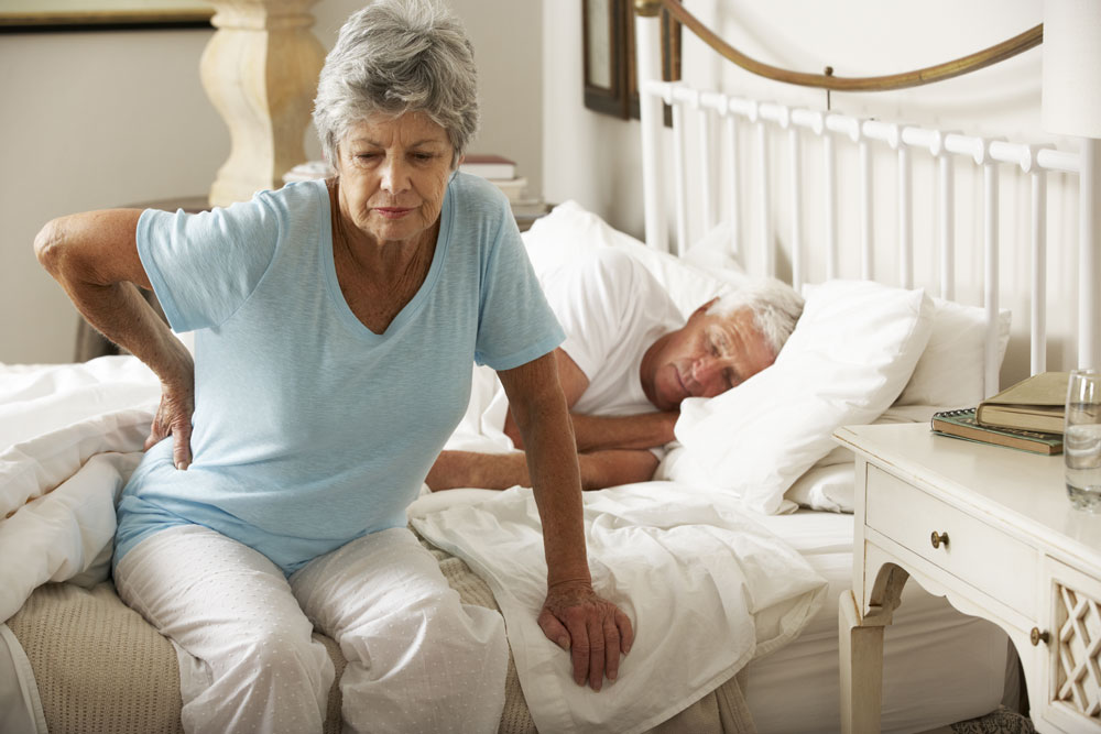 Elderly lady with back pain getting out of bed