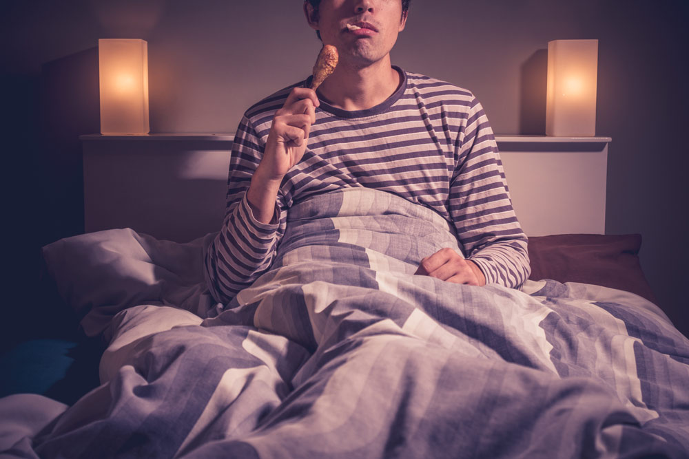 man eating food in bed