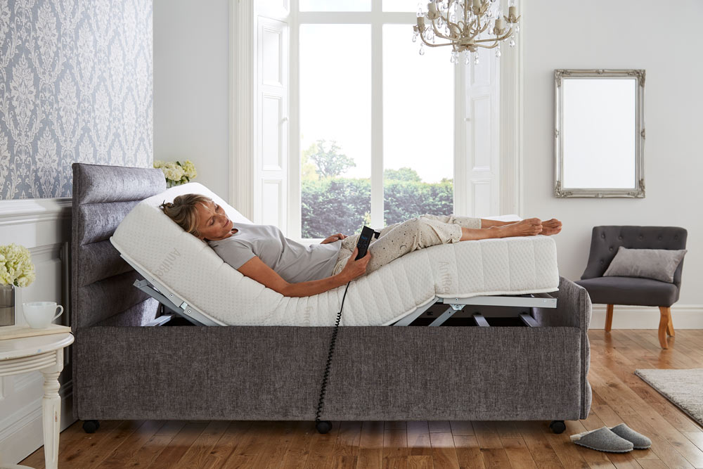 Women enjoying full support in her adjustable bed holding the hand control