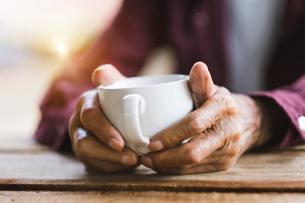 Elderly person holding a cup of coffee