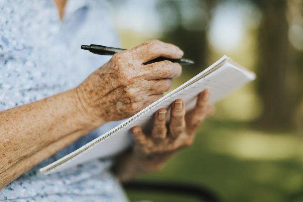 Elderly person taking notes in a journal